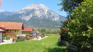 Panoramablick auf die majestätischen Berge und die umliegende Wohngegend mit grünen Wiesen.
