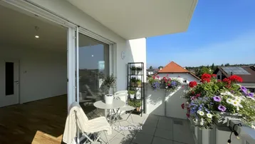 Möblierter Balkon mit Fliesenboden und Blumenkästen, ideal für entspannte Stunden im Freien.