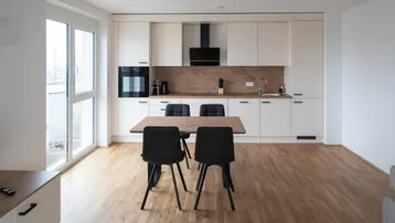 Moderne offene Küche mit integriertem Essbereich, Holzboden und Zugang zu einem Balkon.