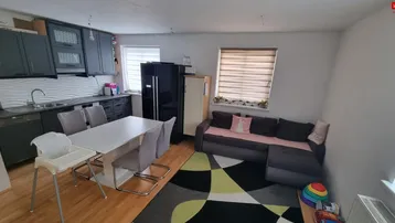 Offener Wohn- und Essbereich mit integrierter Küche, Holzboden und gemütlichem Sofa.