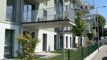 Moderne Wohnanlage mit mehreren Balkonen und begrünten Terrassen im Erdgeschoss.
