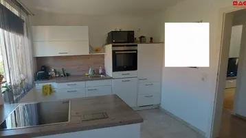 Moderne Küche mit weißen Schränken, Holzarbeitsplatten und einer Kochinsel mit Induktionskochfeld.