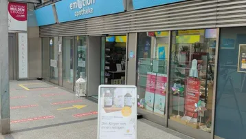 Eingangsbereich einer Apotheke mit blauer Beschilderung und einer Rampe für Barrierefreiheit.