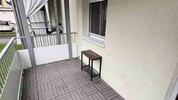 Kleiner Balkon mit grauen Fliesen und einem Beistelltisch, ideal für entspannte Stunden im Freien.