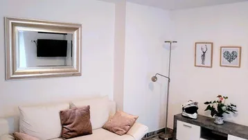 Helles Wohnzimmer mit beigem Sofa, Couchtisch und gemustertem Fliesenboden.