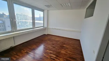 Helles Büro mit großen Fenstern und dunklem Holzparkett, bereit zur individuellen Gestaltung.