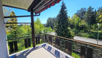 Geräumiger Balkon mit Fliesenboden und schöner Aussicht auf die umliegende Natur und Straße.