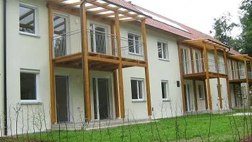 Außenansicht eines modernen Mehrfamilienhauses mit mehreren Balkonen und Holzkonstruktion.