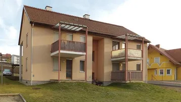 Mehrfamilienhaus mit mehreren Balkonen und Satteldach in ländlicher Umgebung.