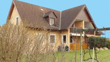 Einfamilienhaus mit Satteldach, Balkon und gepflegtem Gartenbereich im Vordergrund.