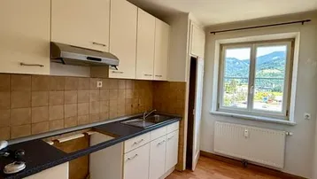 Helle Küche mit Einbauschränken, Laminatboden und einem Fenster mit Bergblick.