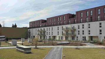 Neubau-Wohngebäude mit moderner Fassade und angelegten Grünflächen im Außenbereich.