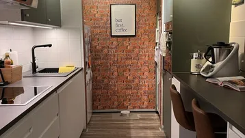 Moderne Küche mit dunkelgrünen Oberschränken, Backsteinwand und kleiner Frühstücksbar.
