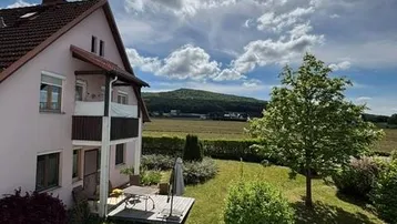 Rückseite des Hauses mit Terrasse, Garten und weitem Blick auf die Landschaft.