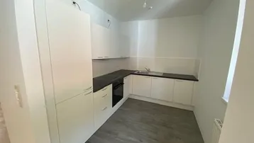 Moderne Einbauküche in Weiß mit dunkler Arbeitsplatte und neuem Vinylboden.