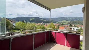 Geräumiger Balkon mit Fliesenboden und weitem Panoramablick über die Stadt und grüne Hügel.