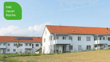 Mehrere moderne Wohngebäude mit roten Ziegeldächern und Balkonen in ländlicher Umgebung.
