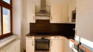 Funktionale Küche mit weißen Schränken, dunkler Arbeitsplatte und modernen Einbaugeräten.