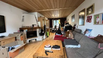 Geräumiges Wohnzimmer mit Kamin, Holzbalkendecke und Laminatboden.