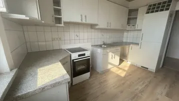 Leere Küche mit weißen Schränken, Granit-Arbeitsplatten und hellem Holzfußboden.
