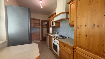 Traditionelle Holzküche mit Gasherd, Backofen und großem Kühlschrank.
