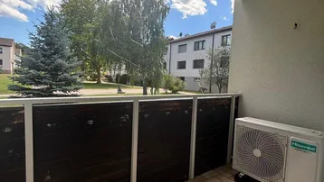 Balkon mit Fliesenboden, Klimaanlage und Blick ins Grüne.