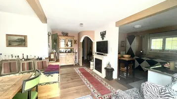 Gemütlicher Wohn- und Essbereich mit Holzboden, sichtbaren Deckenbalken und traditioneller Einrichtung.
