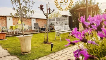 Gepflegter Gartenbereich mit Rasenfläche, Sitzgelegenheiten und einem kleinen Pavillon, ideal zum Entspannen.