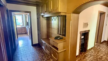 Traditioneller Eingangsbereich mit Holzbalkendecke, Fliesenboden und integrierter Garderobe in warmen Holztönen.
