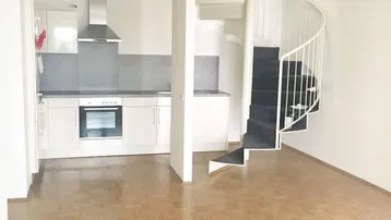 Offener Wohnbereich mit integrierter Küche, Parkettboden und einer eleganten Wendeltreppe.