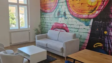 Helles Wohnzimmer mit modernem Wandbild, Parkettboden und bequemen Sitzgelegenheiten.