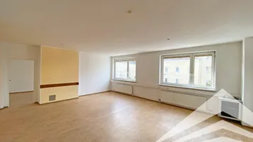 Geräumiger, heller Büroraum mit mehreren Fenstern, Laminatboden und einer Akzentwand.