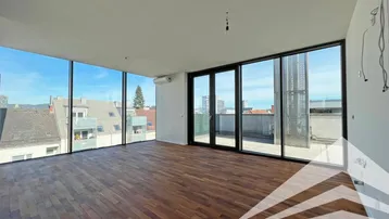 Geräumiger, heller Wohnbereich mit großen Fenstern, Holzboden und Zugang zur Terrasse.