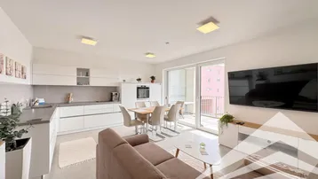 Heller offener Wohn-Essbereich mit moderner Einbauküche und Zugang zum Balkon.