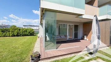 Geräumige Terrasse mit Holzdeck und Sitzgelegenheiten, umgeben von einem gepflegten Rasenbereich.
