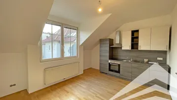 Helle Dachgeschosswohnung mit integrierter Küchenzeile und Holzboden, ideal für offenes Wohnen.