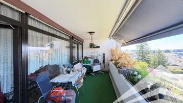 Geräumiger Balkon mit Sitzgelegenheiten, Pflanzen und Markise, ideal für entspannte Stunden im Freien.