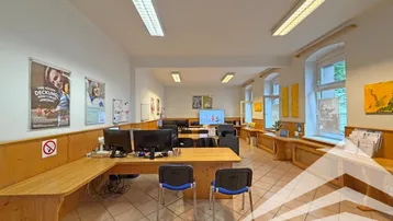 Großes, offenes Büro mit mehreren Arbeitsplätzen, Holzvertäfelung und Fliesenboden, gut beleuchtet durch Fenster.