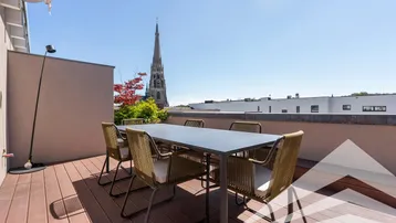 Geräumige Dachterrasse mit Esstisch und Stühlen, bietet einen weiten Blick über die Stadt.