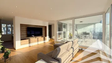 Helles Wohnzimmer mit Holzboden, integriertem TV-Möbel und Zugang zu einer großen Terrasse.