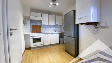 Funktionale Küche mit weißen Schränken, Geräten und einem Warmwasserbereiter, ausgestattet mit Holzboden.