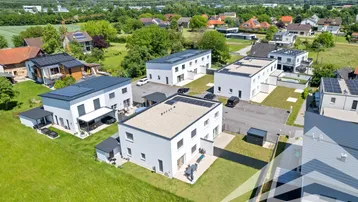 Luftaufnahme einer modernen Wohnsiedlung mit viel Grün und Bergblick.