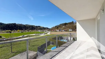 Geräumiger Balkon mit Fliesenboden und Glasgeländer, bietet weite Aussicht auf die Landschaft.