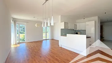 Heller offener Wohn- und Essbereich mit Parkettboden und integrierter Küche, bietet Zugang zum Balkon.