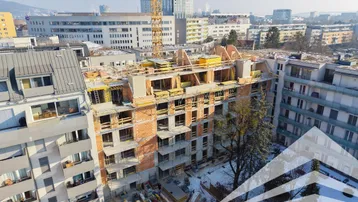 Baustelle eines neuen Wohngebäudes mit Kran und umliegender Stadtlandschaft im Winter.