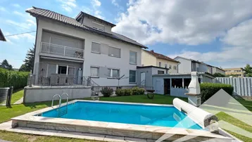 Großzügiger Gartenbereich mit Swimmingpool, Liegewiese und Grillplatz hinter dem modernen Wohnhaus.