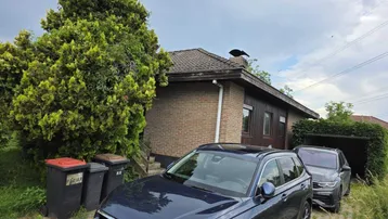 Einfamilienhaus mit Ziegelfassade, Satteldach und geparkten Autos auf der Auffahrt.