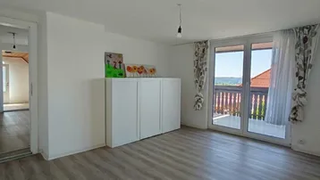 Helles Wohnzimmer mit Laminatboden und direktem Zugang zu einem Balkon mit Aussicht.
