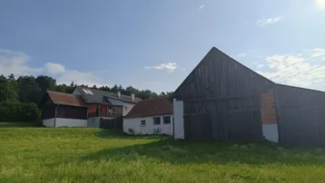 Ländliches Anwesen mit mehreren Gebäuden und weitem Blick über grüne Felder.