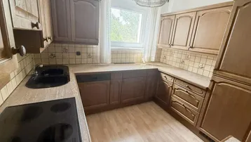 Traditionelle Holzküche mit Einbaugeräten, Spüle und Fensterblick.